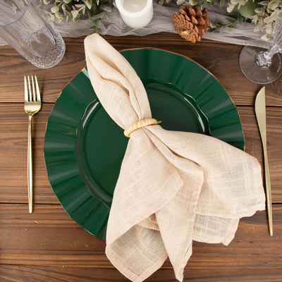 Green dinner plate with beige napkin and wooden ring on a rustic wooden table setting.