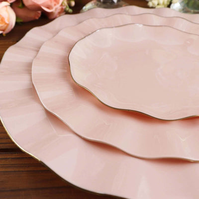 Elegant pink plates with gold rim, stacked on a wooden surface.