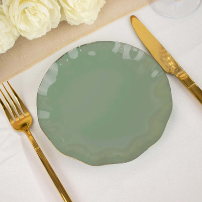 Green scalloped edge plate with gold trim and utensils on a table setting.