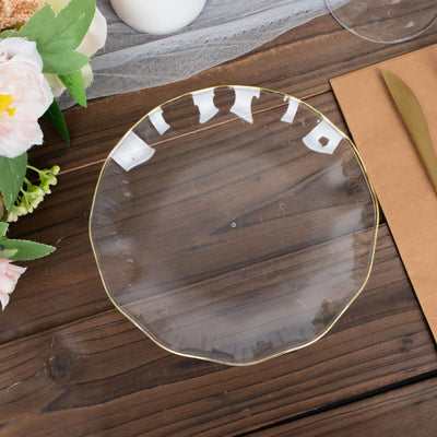 Clear glass plate with gold rim on a wooden table.