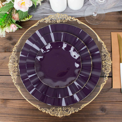 Elegant purple plates with ornate gold trim stacked on a wooden table.