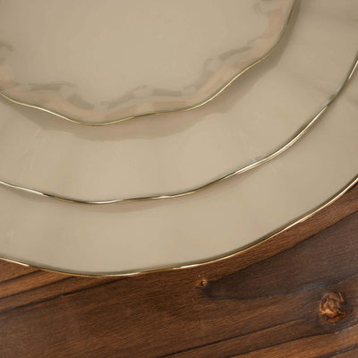 Elegant cream plates with gold trim on a wooden table.