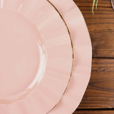 Pink dinner plates with gold trim on wooden table.