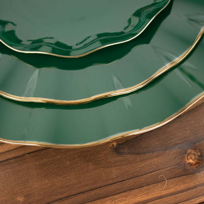 Green decorative plates with gold trim stacked on a wooden surface.