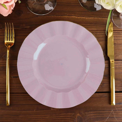 Pink scalloped plate with gold trim on a wooden table setting.