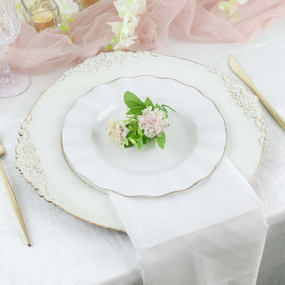 Elegant white dinner plate with floral decoration on a styled dining table setting.