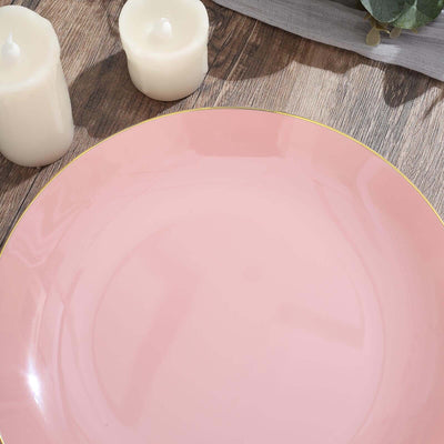 Pink dinner plate with gold rim on wooden surface.