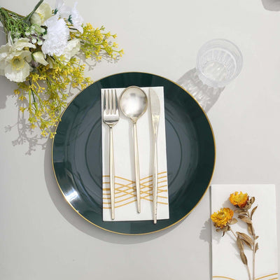 Elegant green plate set with silver cutlery and floral napkin on a table.