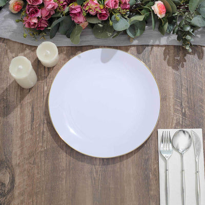 Elegant white plate with gold rim, set on a wooden table with candles and flowers.