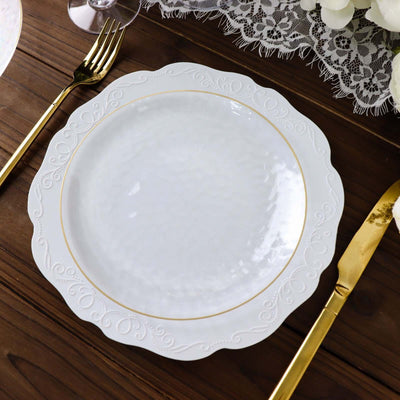 Elegant white dinner plate with gold rim and embossed design on wooden table.