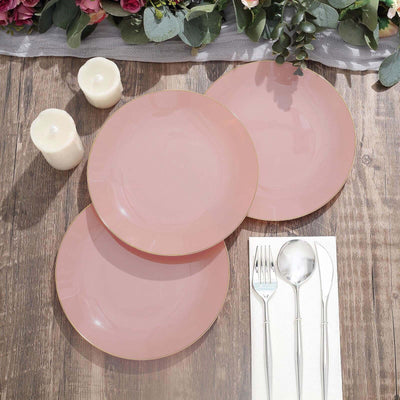 Set of three pink plates with gold trim on a wooden table.