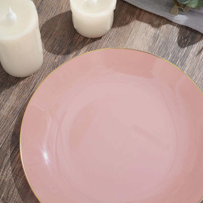Pink plate with gold rim on wooden surface, decorated with candles.