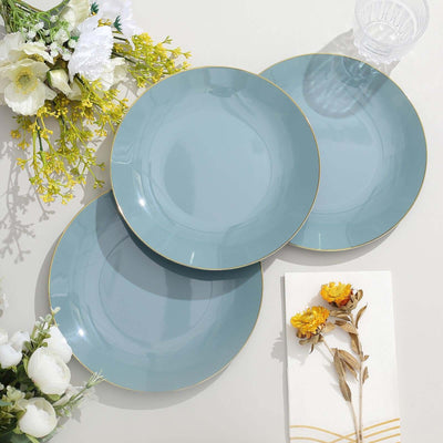 Set of three elegant blue plates with gold trim on a neutral surface.
