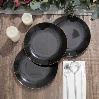 Three elegant black plates with gold trim on a wooden table setting.