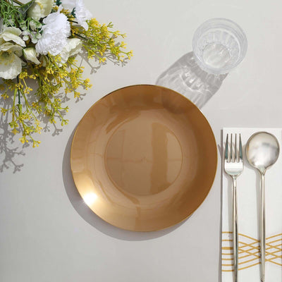 Gold dinner plate with silver cutlery and glass, styled with flowers.