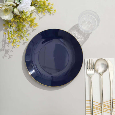 Navy blue plate with gold rim, silver cutlery, and glass on a table setting.