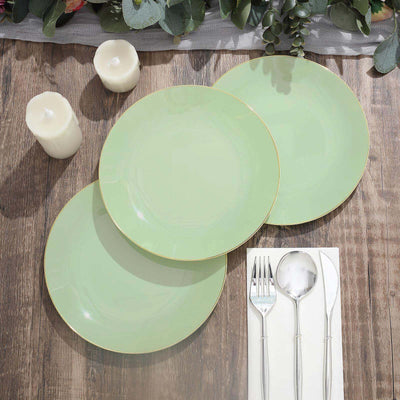 Three elegant mint green plates with gold trim on a wooden table setting.