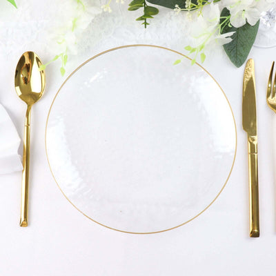Elegant clear glass plate with gold trim, surrounded by gold cutlery.
