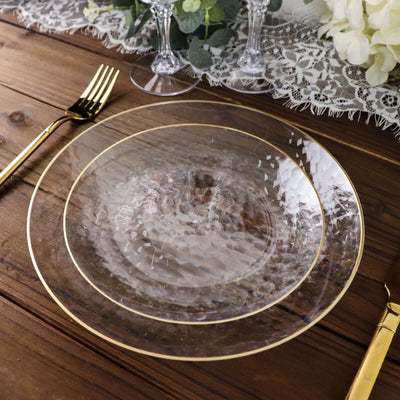 Elegant clear glass plate with gold rim on a rustic wooden table setting.