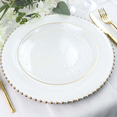 Elegant white plate with gold rim and beaded edge on a decorated table setting.