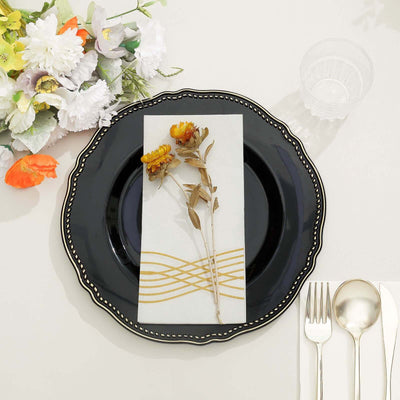 Elegant black plate with floral napkin and cutlery set on a table.