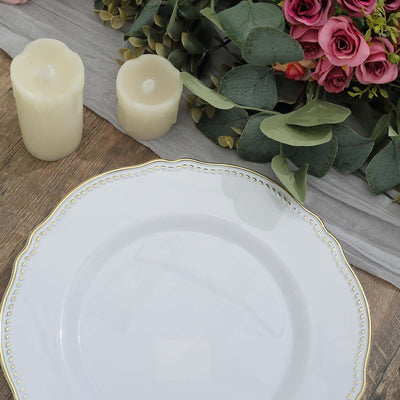 Elegant white plate with gold trim, surrounded by candles and flowers.