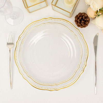 Clear glass plate with gold rim, set with fork and knife on a table.