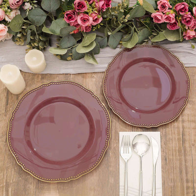 Elegant burgundy plates with decorative edges, surrounded by flowers and candles.