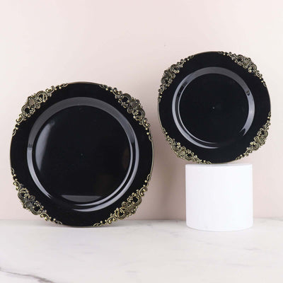 Black decorative plates with gold floral accents on a marble surface.