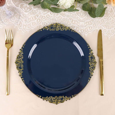 Navy blue decorative plate with gold trim, fork and knife on a table setting.