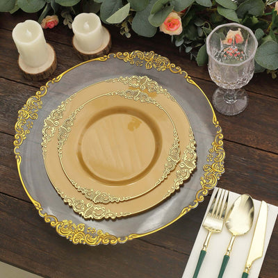 Elegant gold-accented dinner plates set on a rustic wooden table with candles and greenery.