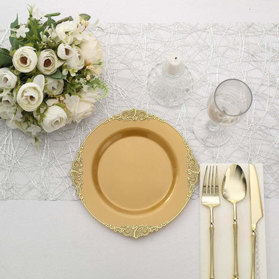 Gold decorative plate with cutlery and floral centerpiece on a table setting.