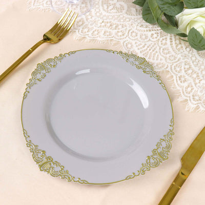 Elegant gray plate with gold ornate rim on beige table setting.