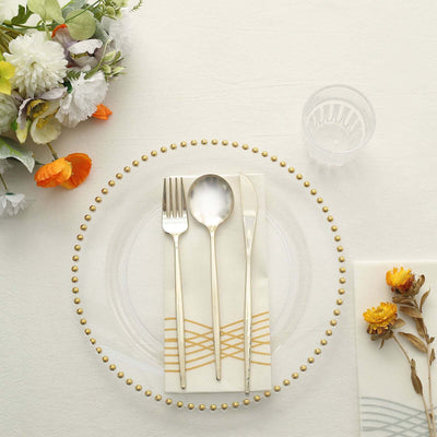 Elegant table setting with gold-accented cutlery and floral decor.