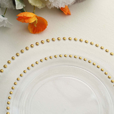 Elegant clear plate with gold beaded rim on textured surface.