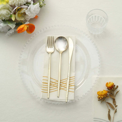 Elegant table setting with silver cutlery, glass plate, and decorative napkin.