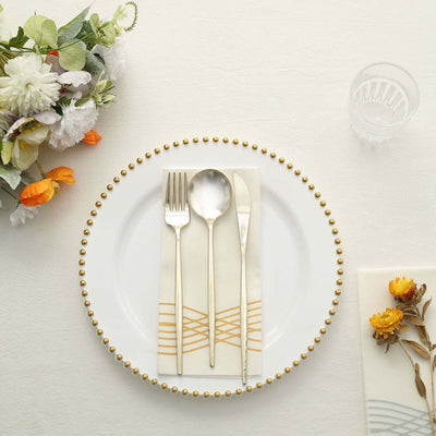 Elegant table setting with gold cutlery and decorative napkin on a white plate.