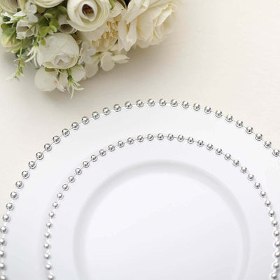 Elegant white plates with silver beaded trim, styled with floral arrangement.