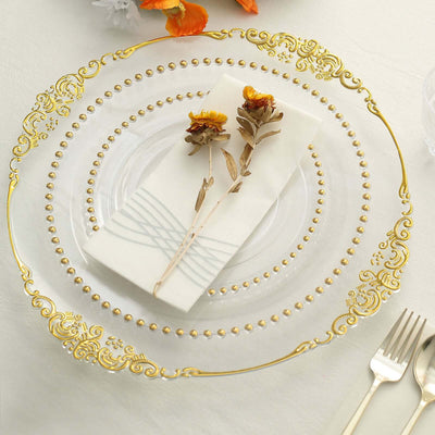 Elegant clear plate with gold trim, napkin, and dried flowers on a table setting.