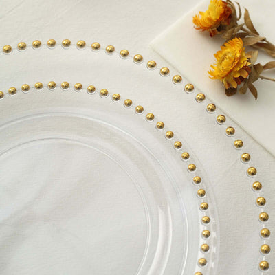 Clear glass plate with golden bead details and dried flowers on a soft background.