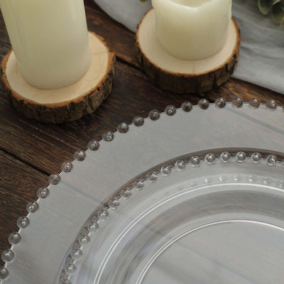 Clear decorative plate with beaded edge next to candles on a wooden surface.