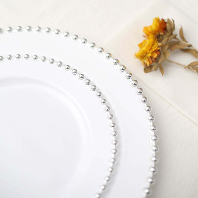Elegant white plates with silver beaded rim and dried flowers.