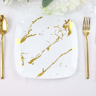 Square white plate with gold marble design, surrounded by gold utensils.
