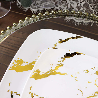 Elegant white plates with gold splatter design on a wooden table setting.