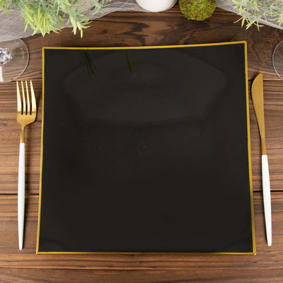 Black square plate with gold trim on a wooden table setting.