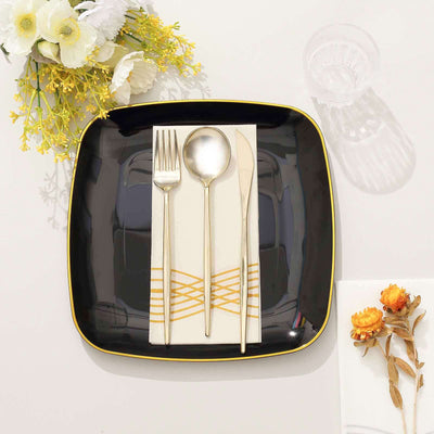 Elegant black square plate with gold-accented cutlery and napkin.