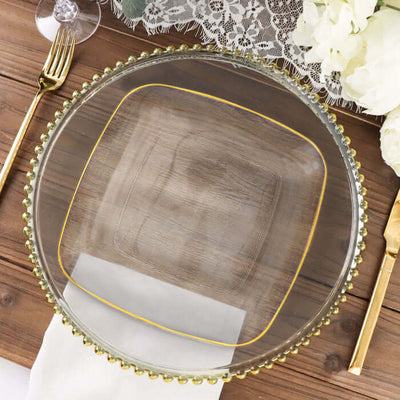 Elegant clear glass plate with gold trim and beaded edge on rustic wooden table.