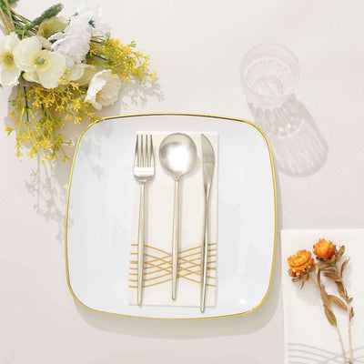 Elegant white dinner plate with gold trim, silver cutlery, and decorative napkin.