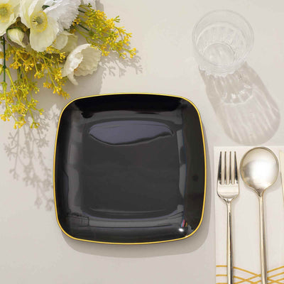 Black square plate with yellow rim, set on a table with cutlery and flowers.