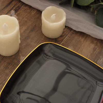 Black square plate with yellow rim beside decorative candles on wooden table.